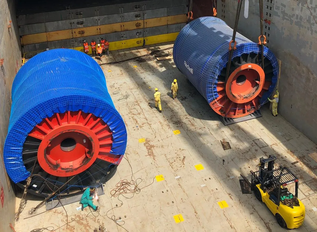 Two cable reels stowed in the hold, crew checking the sea-fastening